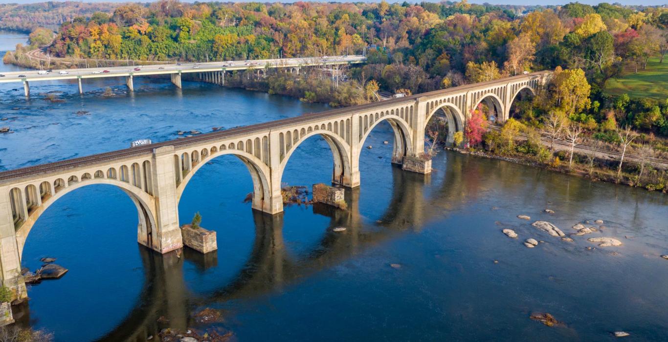 Railroad bridge arches over the James River in autumn